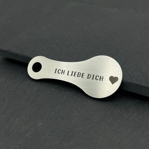 May include: A silver key chain with a heart and the text "ICH LIEBE DICH" engraved on it.