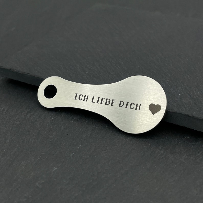 May include: A silver key chain with a heart and the text "ICH LIEBE DICH" engraved on it.