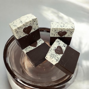 May include: Three bars of handmade soap with a white and brown swirl design. Each bar has a heart-shaped design in the center.