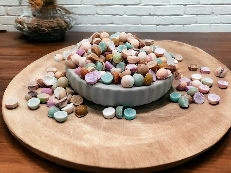 May include: A bowl filled with colorful candy, some of the candy is broken in half, and the candy is scattered on a wooden surface.