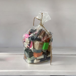 Peut inclure: Un sac en plastique transparent rempli de différents savons colorés. Les savons sont de formes et de tailles variées, notamment des carrés, des rectangles et des cercles. Les savons sont d'un mélange de couleurs, notamment rose, vert, marron et noir.