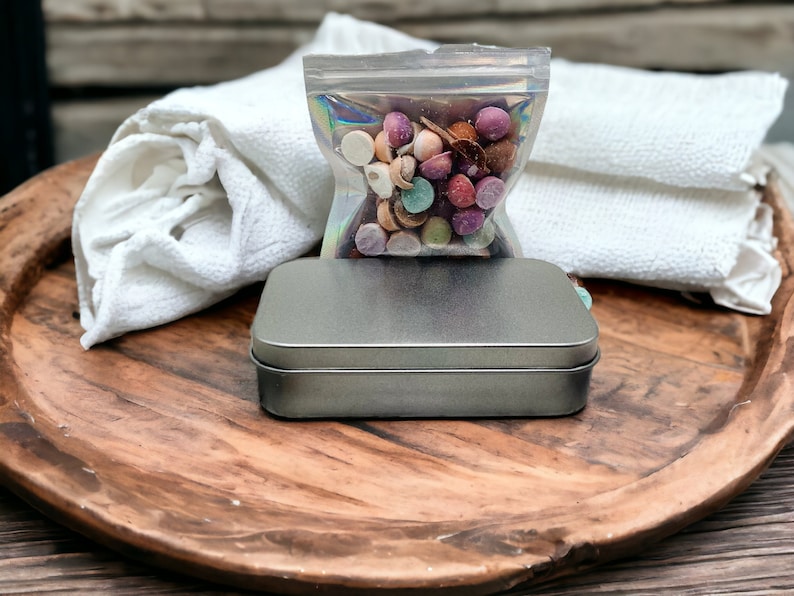 May include: A wooden tray with a silver metal tin, a white cloth, and a clear plastic bag filled with colorful candy.