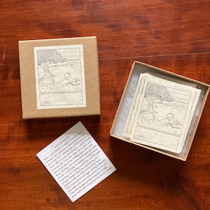 May include: Two small, rectangular, beige boxes. One box is closed, and the other is open, revealing several small cards with a black and white illustration. A small white paper with text is also present. The text reads "WHEAT PASTE".