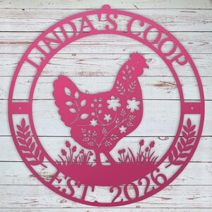 Decorative metal pink sign with a chicken silhouette and text on a wooden background