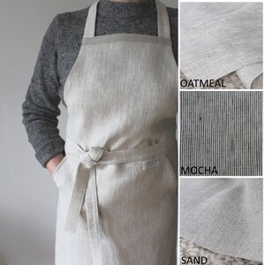 May include: A linen apron with adjustable straps and a large pocket. The apron is available in three colours: Oatmeal, Mocha, and Sand.