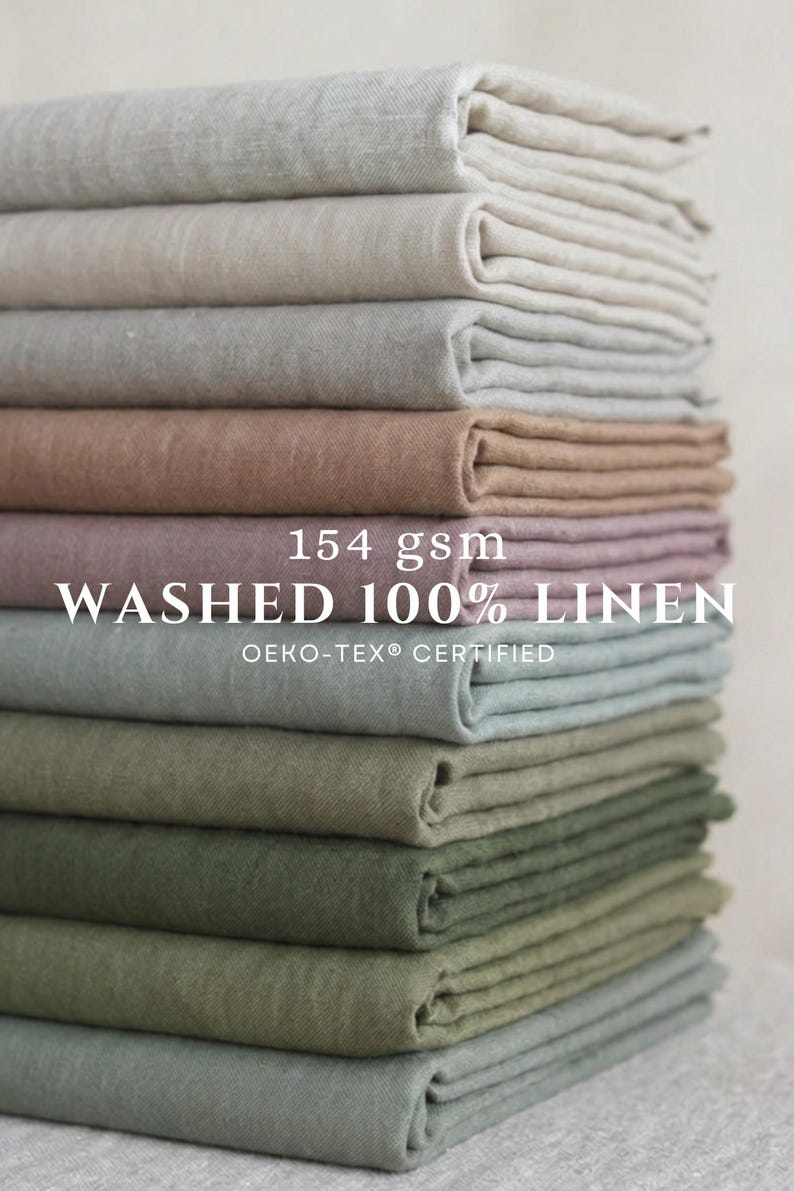 May include: A vertical stack of folded fabric pieces in various neutral and earthy tones including beige, gray, mauve, and shades of green. The text 154 gsm WASHED 100% LINEN OEKO-TEX CERTIFIED is printed in white across the center of the stack.