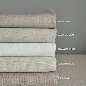Op de afbeelding: Vijf verschillende tinten linnen stof gestapeld op elkaar. De kleuren zijn: Alma Sand, Alma Oatmeal, Alma Off White, Mira Oatmeal en Mira Sand.