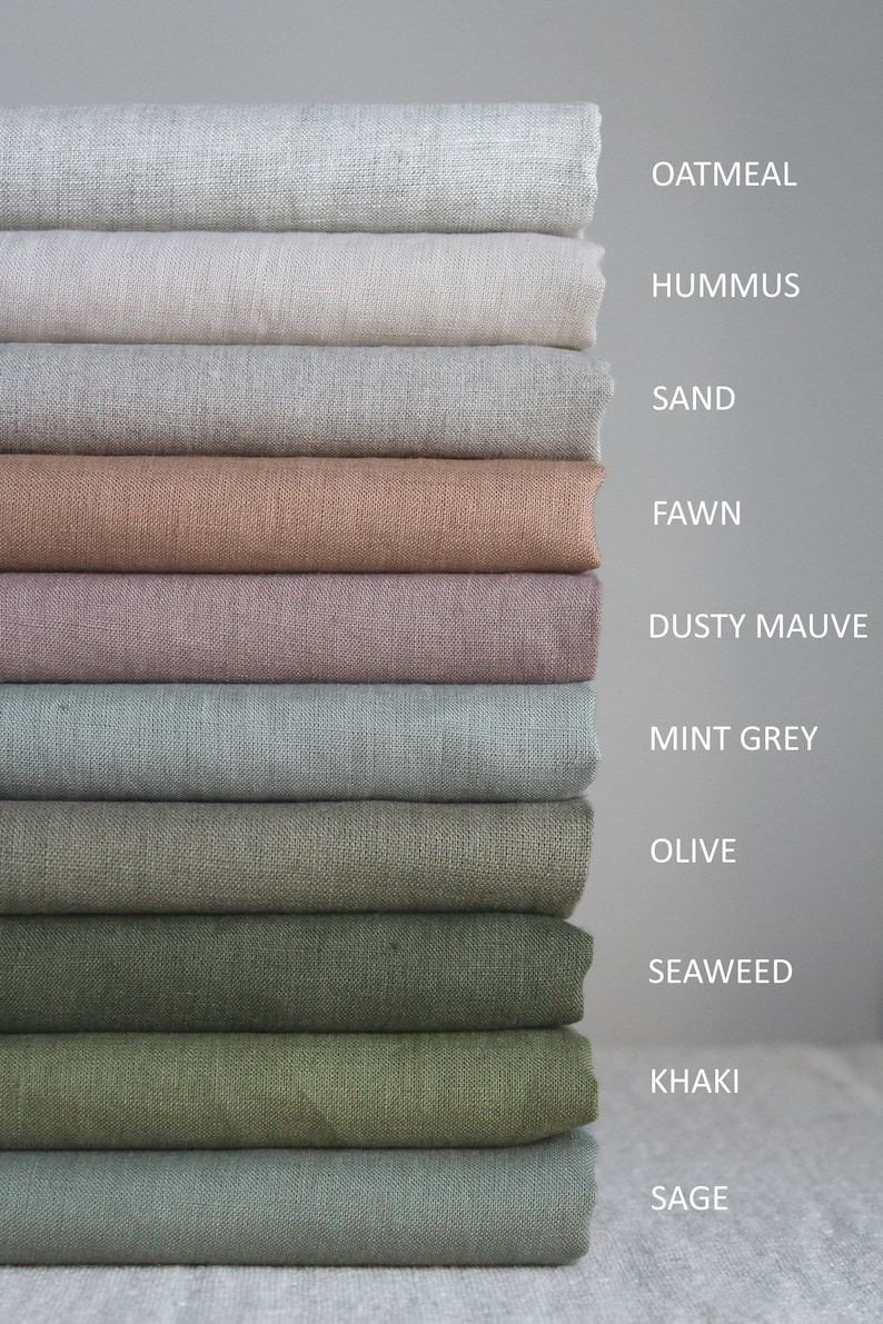 Op de afbeelding: Een stapel van tien stofstalen in verschillende tinten beige, bruin, groen en grijs. De stalen zijn gelabeld met de volgende namen: Oatmeal, Hummus, Sand, Fawn, Dusty Mauve, Mint Grey, Olive, Seaweed, Khaki en Sage.
