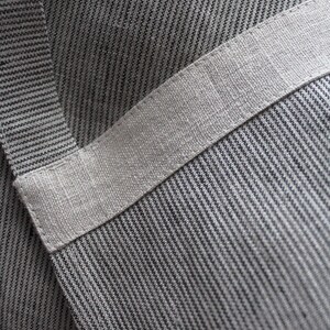 May include: Close-up of a grey and white striped fabric with a white band across the middle. The fabric has a textured, woven look.