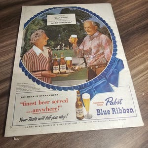 Puede incluir: Anuncio vintage de cerveza Pabst Blue Ribbon. El anuncio presenta a una pareja brindando con vasos de cerveza, con botellas y vasos en una bandeja. El texto incluye "finest beer served...anywhere!" y "Pabst Blue Ribbon".