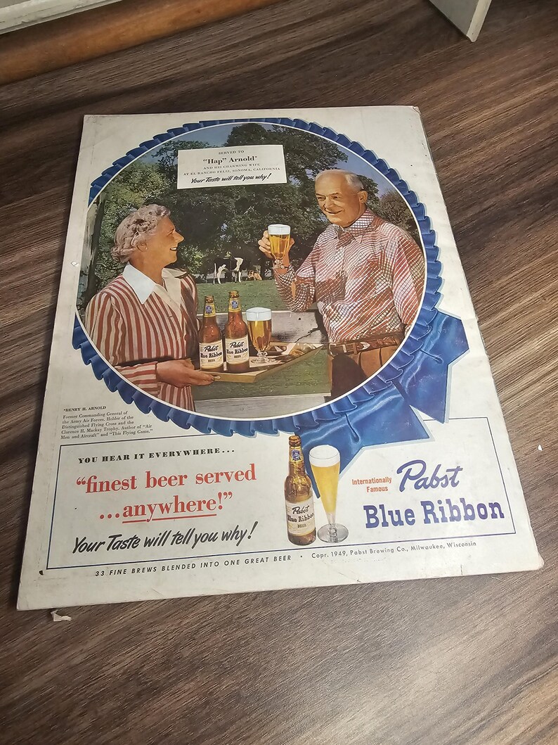 Puede incluir: Anuncio vintage de cerveza Pabst Blue Ribbon. El anuncio presenta a una pareja brindando con vasos de cerveza, con botellas y vasos en una bandeja. El texto incluye "finest beer served...anywhere!" y "Pabst Blue Ribbon".