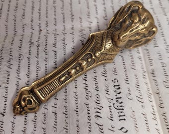 May include: A brass animal head paperweight with a detailed design. The paperweight is in the shape of a dog's head with a long, slender handle.