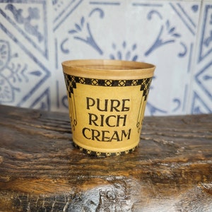 May include: A brown paper cup with black and gold trim. The cup says "Pure Rich Cream" in black lettering.