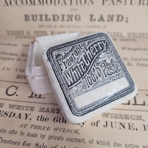 Antiker Topfdeckel und Boden, antike Apothekenwerbung weißer Keramik, duftende weiße Kirschzahnpasta, quadratischer Topfdeckel, viktorianische Werbung
