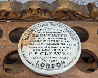 May include: Vintage white ceramic lid for a tooth powder jar. The lid has black lettering that reads "Saponaceous Tooth Powder Prepared from Pure White Soap as Recommended by Dr. Bowditch Being the Only Dentifrice Calculated to Preserve and Thoroughly Cleanse the Teeth Rendered Agreeable for Use & Delicately Scented by F.S.Cleaver 32 & 33 Red Lion Street Holborn London."