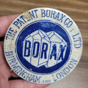 May include: A white ceramic lid with blue lettering and a blue and white logo. The lid reads "The Patent Borax Co., Ltd Birmingham and London" and features a logo of a blue and white crystal with the word "Borax" in white lettering.