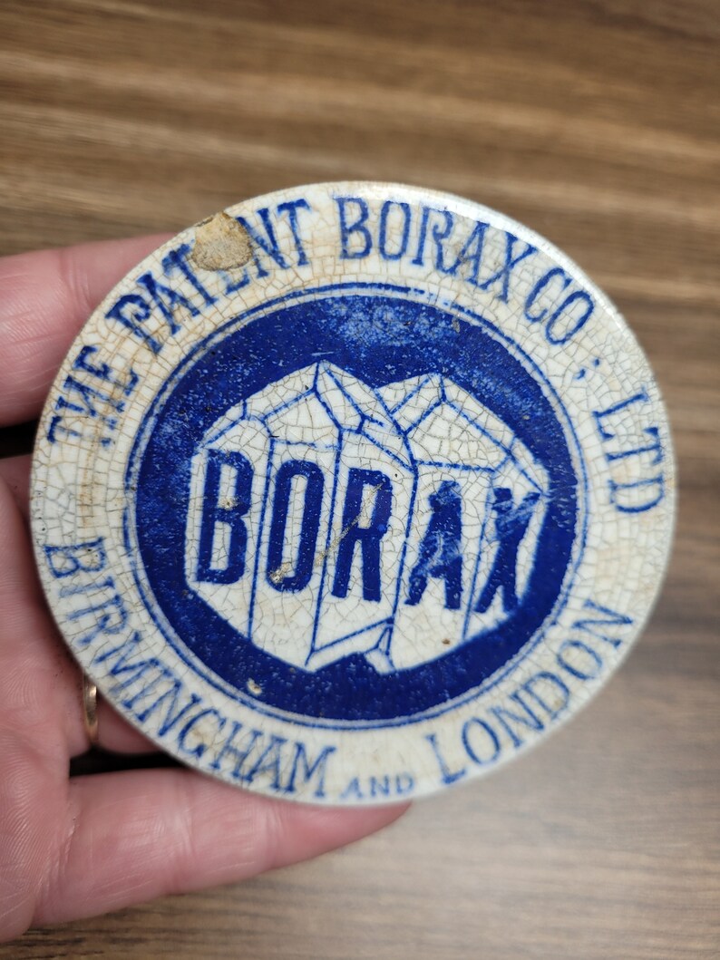 May include: A white ceramic lid with blue lettering and a blue and white logo. The lid reads "The Patent Borax Co., Ltd Birmingham and London" and features a logo of a blue and white crystal with the word "Borax" in white lettering.