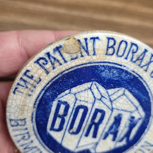 May include: A vintage ceramic lid with a blue and white design. The lid features the text "The Patent Borax Birmingham and London" and a blue and white image of the word "Borax" in a geometric shape.