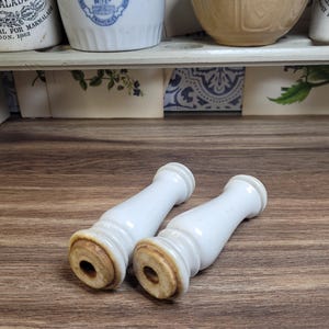 May include: Two white ceramic drawer pulls with a rounded, fluted design. The pulls have a slightly aged, off-white color.