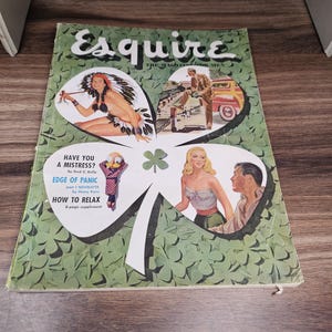 Puede incluir: Portada de la revista Esquire vintage con un dise&ntilde;o de tr&eacute;bol verde. La portada presenta ilustraciones de una mujer con un tocado nativo americano, un hombre con un coche y una pareja. El texto incluye "Esquire" y "&iquest;Tienes una amante?"