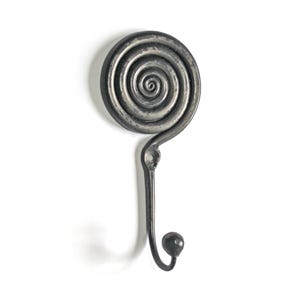 Puede incluir: Un gancho de pared de metal gris oscuro con un diseño de espiral circular en la parte superior y un gancho curvo que termina en una pequeña perilla esférica. La pieza incluye un orificio de montaje debajo de la sección en espiral.