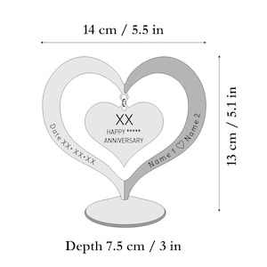 Puede incluir: Adorno de aniversario en forma de coraz&oacute;n plateado, de 14 cm de ancho, 13 cm de alto y 7,5 cm de profundidad. Presenta un coraz&oacute;n central con "HAPPY ANNIVERSARY" y espacio para nombres y una fecha. Un regalo atento.