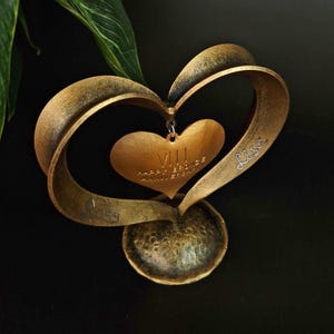 Puede incluir: Escultura en forma de coraz&oacute;n de color bronce con un colgante m&aacute;s peque&ntilde;o en forma de coraz&oacute;n. El colgante dice "VIII HAPPY BRONZE ANNIVERSARY". La escultura tiene el nombre "Lisa" y el n&uacute;mero "0055".