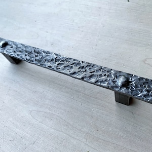 May include: A hammered metal door handle with a textured surface and a silver finish.