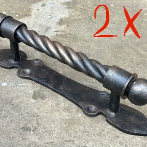 May include: Two black metal door handles with a twisted design. The handles have a rounded end and a flat base with a decorative design.