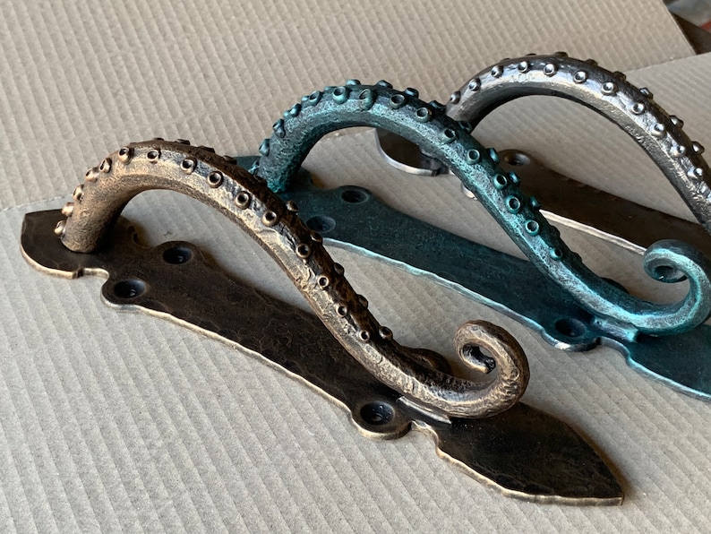 May include: Three octopus-shaped door handles with a decorative, ornate design. The handles are made of metal and are finished in bronze, teal, and silver.