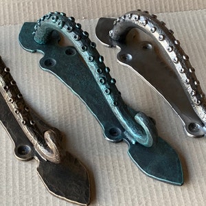 May include: Three octopus-shaped door handles in different finishes: antique brass, aged bronze, and verdigris. Each handle features a detailed design with textured tentacles and a curled tail.