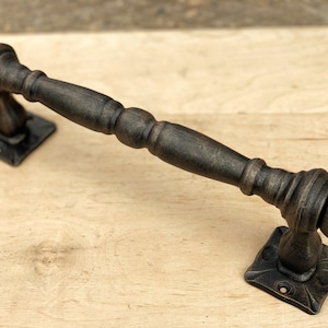 Könnte beinhalten: Schwarzer Türgriff aus Metall mit abgerundetem Design und quadratischen Grundplatten.