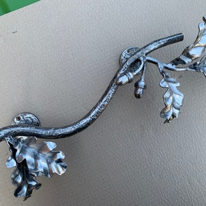 May include: A silver metal door handle shaped like a branch with oak leaves and acorns.