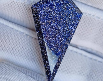 May include: A dark blue, faceted, gemstone pendant with a sparkly, glittery finish.