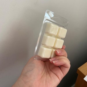May include: A clear plastic pack containing six white wax melts. The wax melts are square shaped and are arranged in two rows of three.