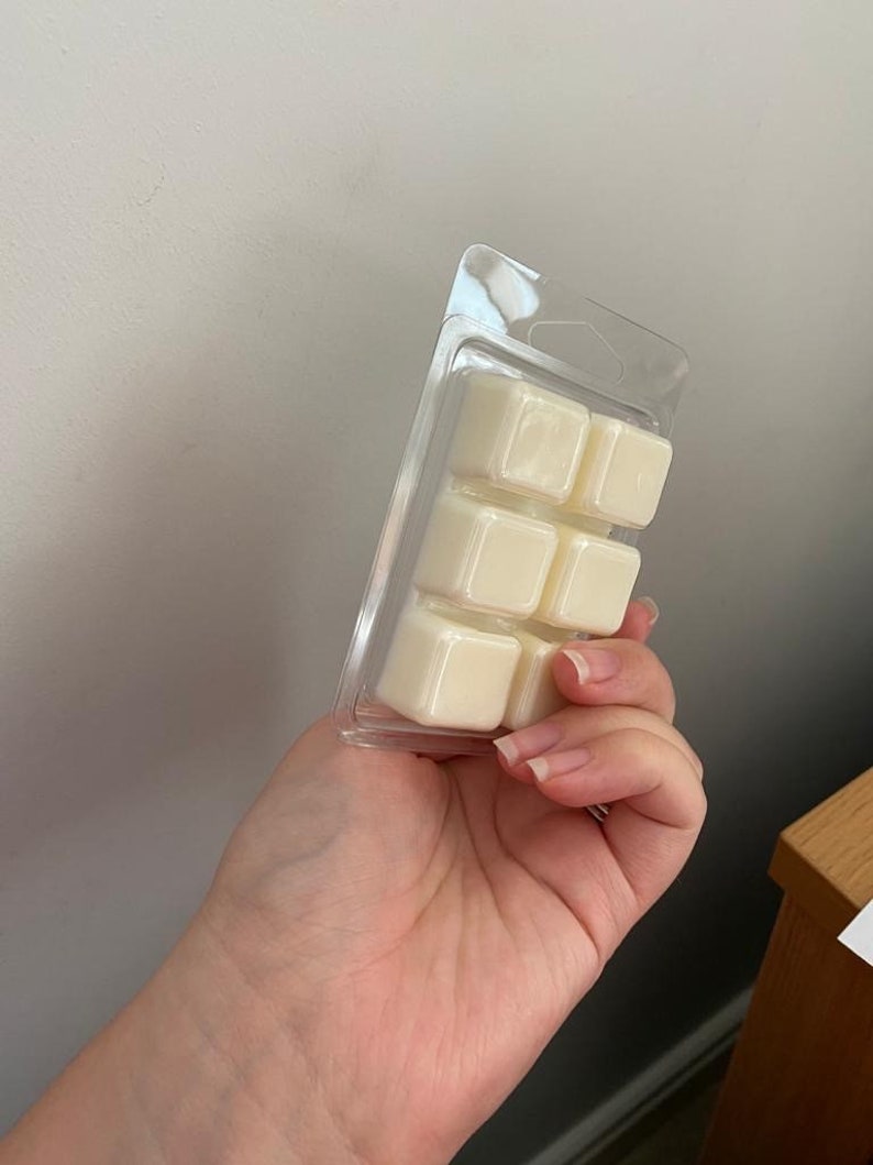 May include: A clear plastic pack containing six white wax melts. The wax melts are square shaped and are arranged in two rows of three.
