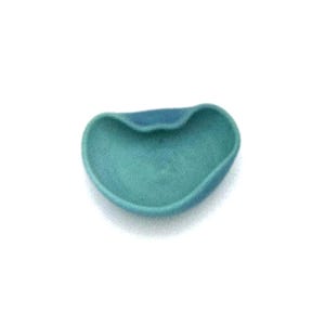 May include: A small, teal-colored, heart-shaped dish with a curved design. The dish has a smooth texture and a slightly darker blue accent on the top edge. The object is set against a plain white background.