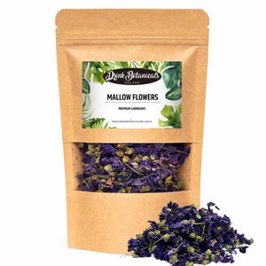 Può includere: Un sacchetto di carta marrone con una finestra trasparente, pieno di fiori di malva viola essiccati. La borsa ha un'etichetta che recita "Drink Botanicals Ireland Mallow Flowers Premium Garnishes". Un piccolo mucchio di fiori è davanti.