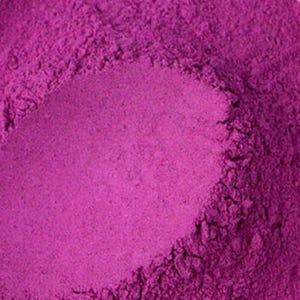 May include: Close-up of a pile of vibrant magenta-colored powder. The powder has a fine, granular texture and appears to be evenly distributed, with subtle variations in tone. The image is well-lit, highlighting the color and texture.