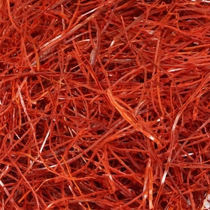 May include: Close-up of a pile of bright red chili threads. The threads are thin, delicate, and have a slightly textured appearance. The image is a close-up, showing the intricate details of the spice.