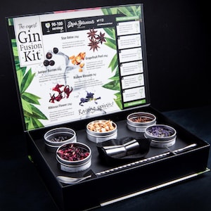 May include: A Gin Fusion Kit with various botanicals, including juniper berries, star anise, and hibiscus flower. The kit includes a mixing spoon, a jigger, and small tins of ingredients. The box is black with a printed lid that includes instructions and the text "Raising spirits!"