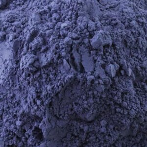 May include: Close-up of a pile of finely ground, deep blue powder. The powder has a textured, granular appearance, with varying shades of blue creating depth and dimension. The image is well-lit, highlighting the texture.