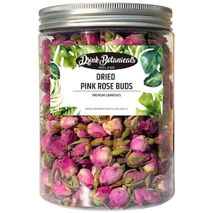 Puede incluir: Un tarro de plástico transparente lleno de capullos de rosa rosa secos. El tarro tiene una tapa plateada y una etiqueta que dice "Drink Botanicals Ireland" y "Dried Pink Rose Buds". La etiqueta también incluye las palabras "Premium Garnishes".