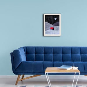 May include: A framed print of a minimalist landscape with a small red house in the distance. The sky is black with white stars and a white moon. The hills are grey and white.