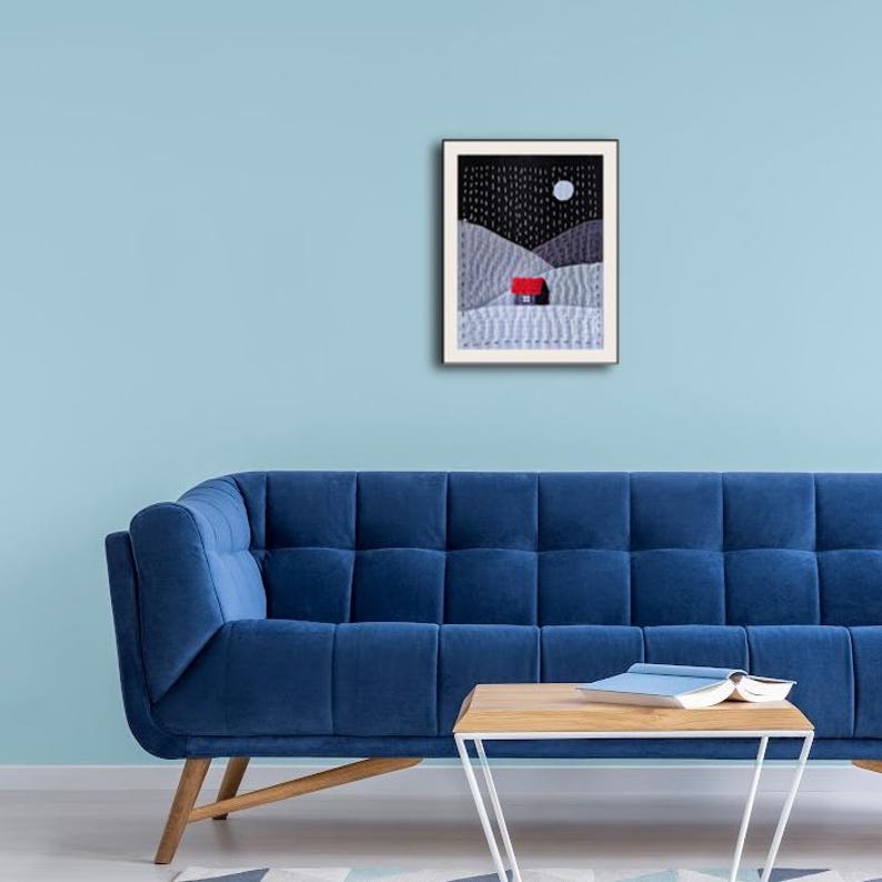 May include: A framed print of a minimalist landscape with a small red house in the distance. The sky is black with white stars and a white moon. The hills are grey and white.
