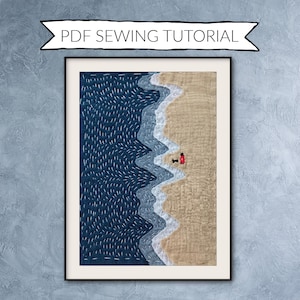 Peut inclure: Art textile encadré représentant une scène de plage avec une mer bleu foncé, des vagues blanches et du sable beige. Une petite figurine rouge se tient près du bord de l'eau. Le texte "PDF SEWING TUTORIAL" est au-dessus du cadre.