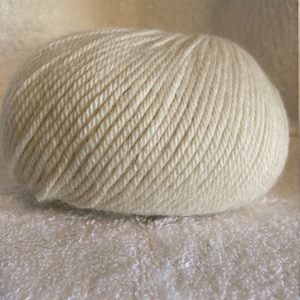 May include: A ball of off-white yarn, wound into a tight coil.