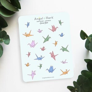 May include: A sheet of colorful origami crane stickers with the text "Angel + Hare Origami Cranes Sticker Sheet" and the website "angelandhare.com".
