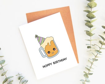 Könnte beinhalten: Eine weiße Karte mit einer Cartoon-Illustration eines Bierbechers mit einer Partymütze. Der Text "Hoppy Birthday" ist unter dem Becher gedruckt.