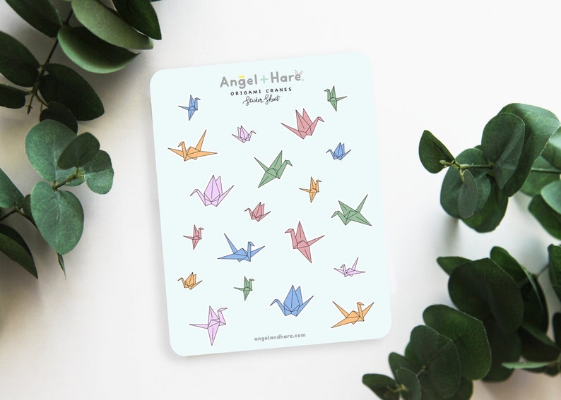 May include: A sheet of colorful origami crane stickers with the text "Angel + Hare Origami Cranes Sticker Sheet" and the website "angelandhare.com".